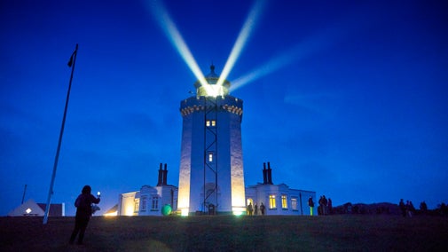 Image showing the intense white light beams from the lighthouse lantern against a dark evening sky